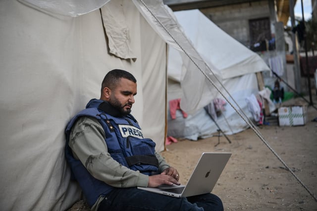 RAFAH, GAZA - JANUARY 14: A press member is seen sitting next to a tent as he tries to connect to the internet while he and his colleagues in Gaza face high risks trying to cover the Israel-Gaza war on January 14, 2024 in Rafah, Gaza. Israeli forces are dropping phosphorus bombs from the sky on people in the besieged Gaza Strip while prohibiting journalists from entering military zones. Nevertheless, photos taken by journalists was later used as clear evidence of Israel's use of phosphorus bombs in Gaza. Journalists who took shelter in Rafah due to the Israeli attacks are trying to provide food and supplies for their families, while also struggling to show what is really happening in Gaza to the world. (Photo by Abed Zagout/Anadolu via Getty Images)