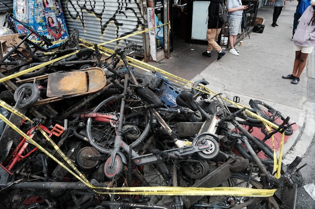 Charred remains of e-bikes and scooters sit outside of a building in New York City's Chinatown after four people were killed by a fire in an e-bike repair shop overnight in June 2023.