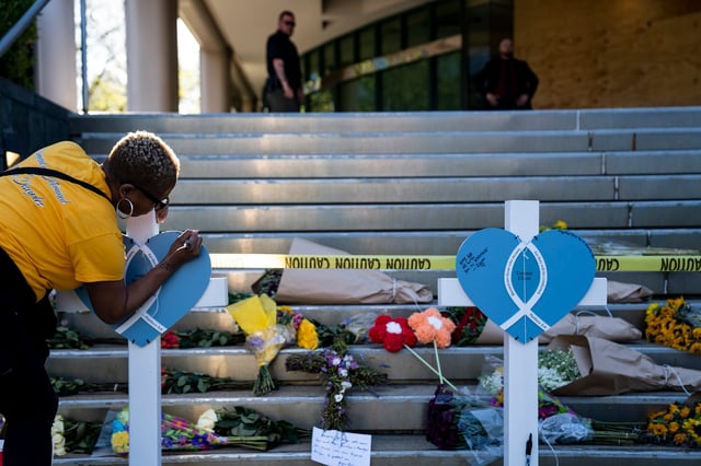 A woman writes a message on the memorial set up for victims of the April 10, 2023 shooting at the Old National Bank in Louisville, Kentucky