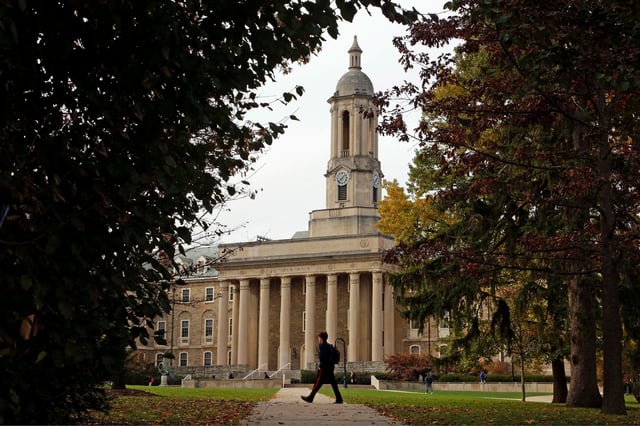 People walk by Old Main on the Penn State University main campus in State College, Pennsylvania, in 2017.
