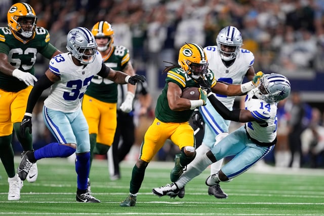 Green Bay Packers running back Aaron Jones (33) applies a stiff-arm on Dallas Cowboys safety Markquese Bell (14) while rushing for yardage during the first half of an NFL football game, Sunday, Jan. 14, 2024, in Arlington, Texas. 