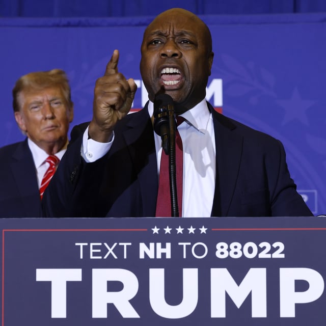 Sen. Tim Scott (R-SC) speaks as Republican presidential candidate and former President Donald Trump looks on during a campaign rally at the Grappone Convention Center on January 19, 2024 in Concord, New Hampshire. Scott was confronted on Sunday over his past remarks opposing "victimhood" and "grievance" in the speech he gave while launching his presidential campaign, as those remarks are at odds with his recent endorsement of Trump.