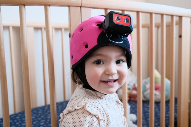 A baby wearing the helmet-mounted camera researchers used to collect a baby's-eye view dataset.