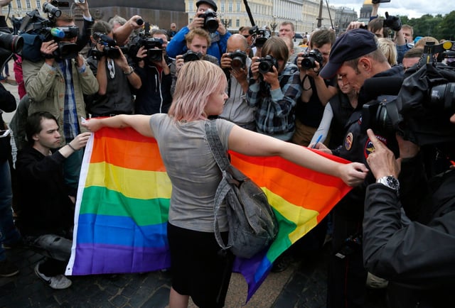 An activist stands with a rainbow flag in front of journalists during a protest in St Petersburg, Russia. Photo: AP