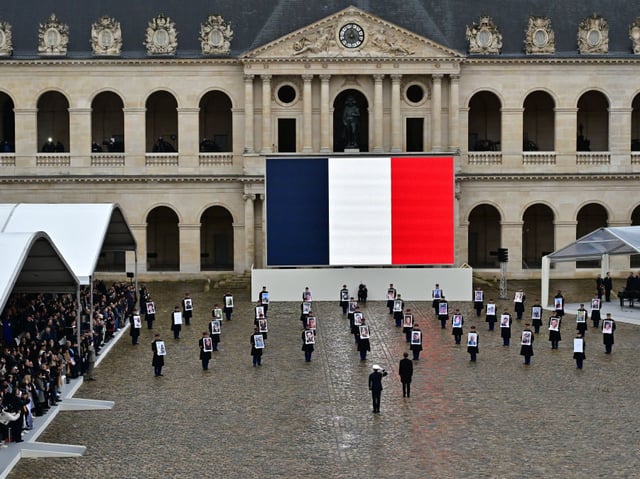 PARIS, FRANCE - FEBRUARY 7: French President Emmanuel Macron (C) stands in front of members of the French Republican Guard (Garde Republicaine) holding portraits of the 42 French and French-Israeli citizens killed,during  on February 7, 2024 in Paris, France. The ceremony pays tribute to the 42 French and French-Israeli citizens killed in the attack on Israel by Hamas and the three others still missing, believed to be held hostage. on Israel by Hamas and the three others still missing, believed to be held hostage. (Photo by Christian Liewig - Corbis/Getty Images)