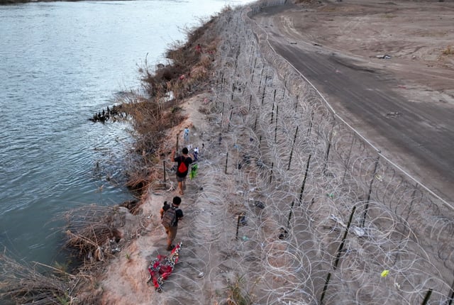 Asylum-seekers walk along a U.S.-Mexico border fence in El Paso, Texas, Feb. 5, 2024.