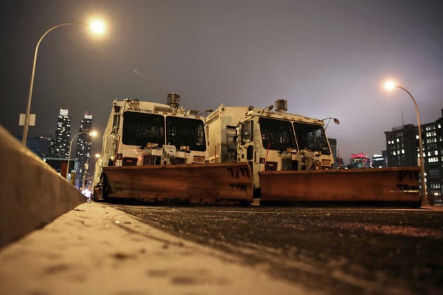 FILE — Sanitation trucks mounted with snow plows are parked on the west side of Manhattan in New York, Jan. 2, 2014. Parts of the Northeast were preparing Monday, Feb. 12, 2024, for a coastal storm that was expected to pack high winds and dump a foot or more of snow in some areas, leading to school closures, warnings against traveling by road and the possible disruption of flights.