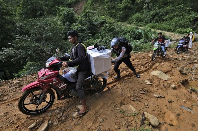 A police officer assists an electoral worker to drive his motorbike up a hill as they distribute ballot boxes and other election paraphernalia to polling stations in remote villages ahead of the Feb. 14 election in Maros, Indonesia, Tuesday, Feb. 13, 2024. Indonesia, the world's third-largest democracy, will open its polls on Wednesday to nearly 205 million eligible voters in presidential and legislative elections, the fifth since Southeast Asia's largest economy began democratic reforms in 1998.