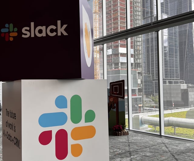Cubes with Slack name and logo stacked on one another with city view in background.