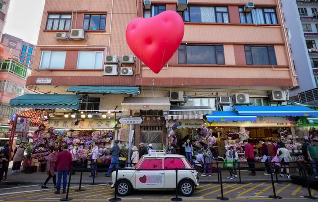 A pop-up “Chubby Hearts” balloon art installation by British fashion designer Anya Hindmarch attached to a classic Mini floats over Flower Street in Mong Kok. Photo: Elson Li