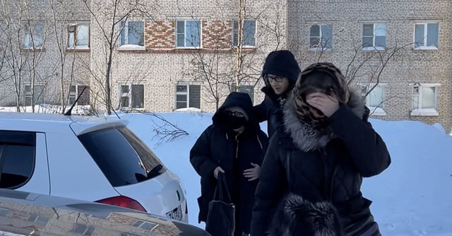 A woman wearing a protective mask and sunglasses, believed to be Lyudmila Navalnaya, the mother of Russian opposition leader Alexei Navalny, is accompanied into a car as she leaves the IK-3 penal colony. REUTERS