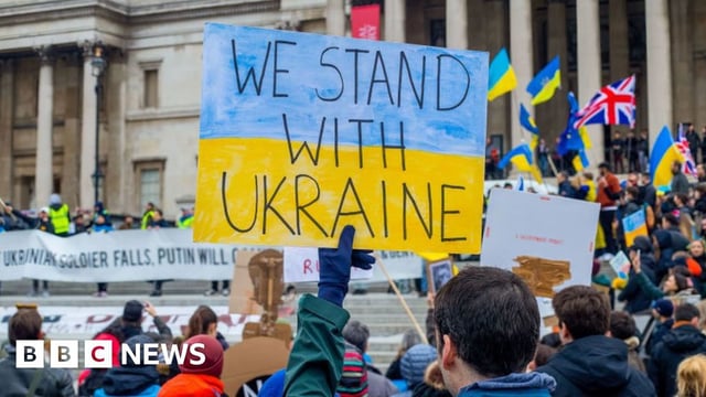 A protester holds a sign saying "We Stand With Ukraine" during a protest against Russia's invasion of Ukraine in London