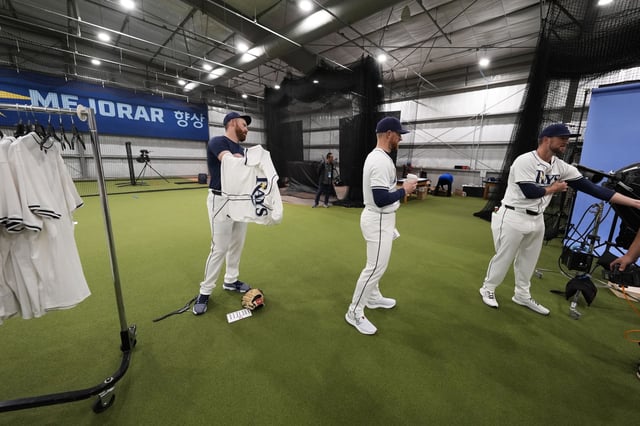 Tampa Bay Rays pitcher Zack Littell, left, dons a uniform for the team's MLB photo day during spring training Sunday, Feb. 18, 2024, in Port Charlotte, Fla.
