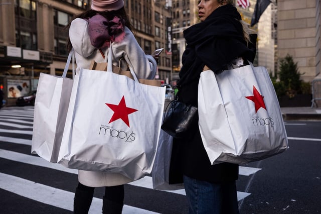 Shoppers carry Macy's bags during "Black Friday" in New York on November 24, 2023, the unofficial start of the holiday shopping season.
