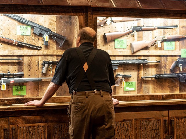 A man looks at cases of firearms in the halls of the Indianapolis Convention Center on Thursday, April 25, 2019, where members of the National Rifle Association will be holding its 148th annual meetings in Indianapolis. The group's meetings come at a tumultuous time within the gun-rights organization. (AP Photo/Lisa Marie Pane)