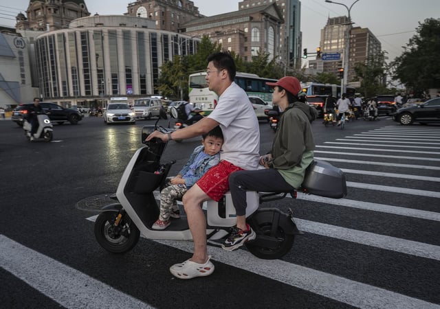 BEIJING, CHINA - SEPTEMBER 13: A boy looks towards a shopping small LCD screen as he waits while riding with his parents on a scooter on September 13, 2023 in Beijing, China.(Photo by Kevin Frayer/Getty Images)