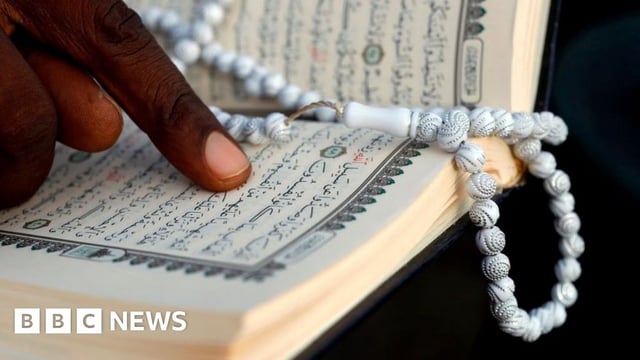 A man reading the Quran with prayer beads.