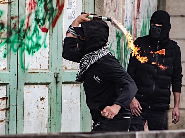 A Palestinian youth hurls a Molotov cocktail against Israeli troops during confrontations with them following a demonstration in the occupied West Bank city of Hebron to show solidary with the Palestinians of the Gaza Strip on October 27, 2023, amid ongoing battles between Israel and Hamas. (Photo by MOSAB SHAWER / AFP) (Photo by MOSAB SHAWER/AFP via Getty Images)