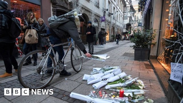 A man on bicycle lays flowers on the street in tribute to the victims of the deadly shooting in central Strasbourg on 12 December, 2018