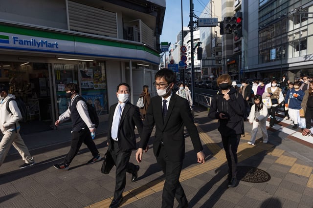 Businessmen walk towards Shinjuku station in Tokyo, Japan.