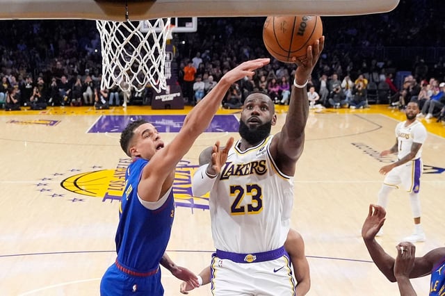 Los Angeles Lakers forward LeBron James, right, scores as Denver Nuggets forward Michael Porter Jr., defends.