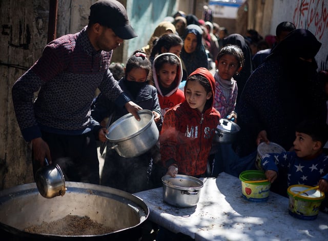 Palestinian children wait to receive food distributed by a charity kitchen, in the southern city of Rafah, on March 5. Israel's military campaign in Gaza has consigned civilians to deadly starvation.