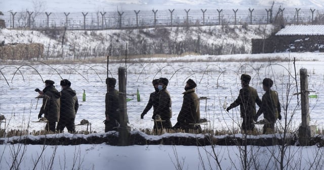 Uniformed border guards patrol next to a fence