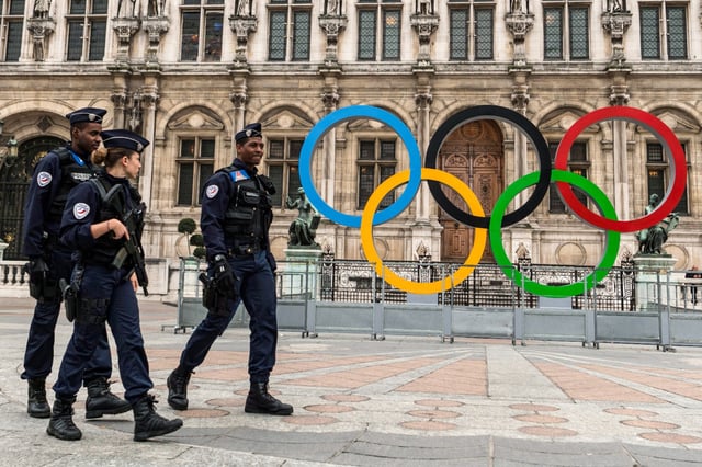 French police walk past Paris' City Hall where the five-Olympic rings are on display, on Oct. 26, 2017, after the city was awarded the 2024 Olympics Games.