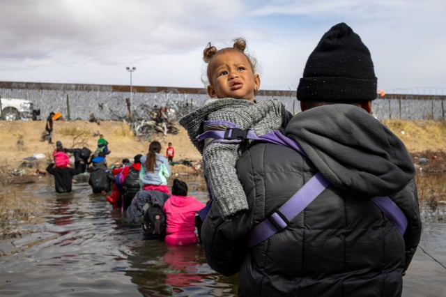 A migrant crosses the Rio Grande with his child attempting to reach the United States border in Ciudad Juarez, Mexico, on Jan. 2, 2024. 