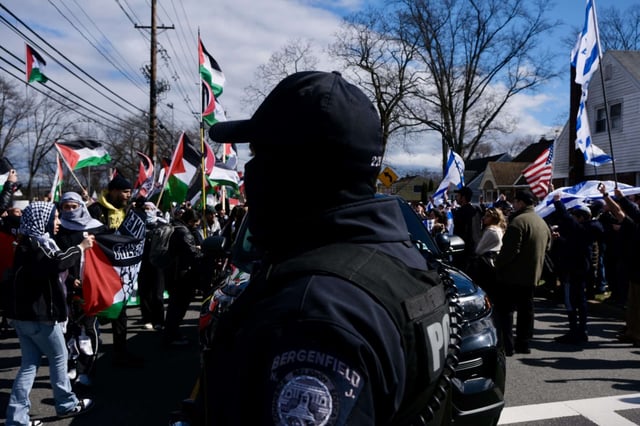 A police officer stands between pro-Palestinian and pro-Israeli protesters in Teaneck, New Jersey on March 10, 2024.