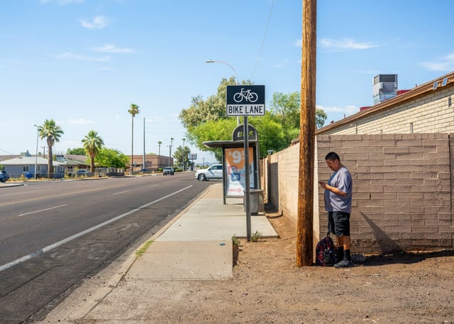 Adrian Mata stands in the shade while waiting for the bus in Phoenix on July 15, 2023.