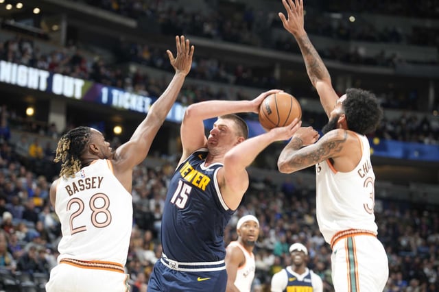 Nuggets center Nikola Jokic, center, drives to the basket as San Antonio Spurs center Charles Bassey, left, and forward Julian Champagnie defend in the second half of a Nov. 26, 2023 game in Denver.