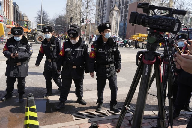 Chinese police officers prepare to push journalists away from the scene of an explosion in Sanhe city, northern China on March 13, 2024.