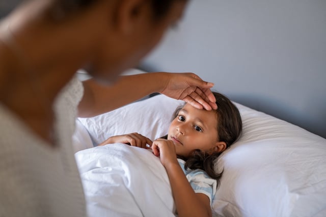 A parent tends to a child with a fever.
