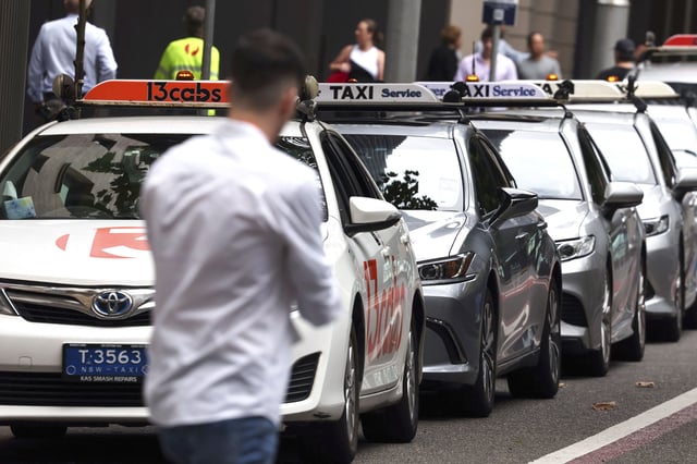 A pedestrian walks past a row of taxis in central Sydney on March 18, 2024. Australian taxi drivers impacted by the rise of ridesharing giant Uber have won US$178 million in compensation, lawyers said on March 18 after settling a gruelling legal battle. More than 8,000 taxi drivers and hire car owners banded together to launch legal action in 2019, arguing they lost substantial income when Uber entered Australia in 2012. (Photo by DAVID GRAY / AFP) (Photo by DAVID GRAY/AFP via Getty Images)