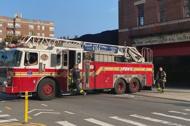 Firefighters jump onto an FDNY truck responding to a call.