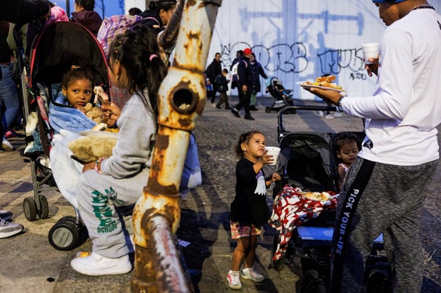 Migrants eat dinner outside of a shelter on the Lower West Side of Chicago on March 4, 2024.