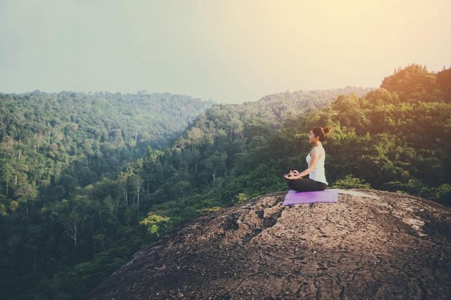 women doing Yoga on rock.