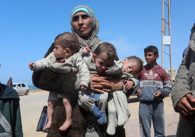 Palestinian woman Nozha Awad flees Al Shifa hospital with her triplets following an Israeli raid, moving southward in central Gaza on Thursday. Photo: Ramadan Abed / Reuters