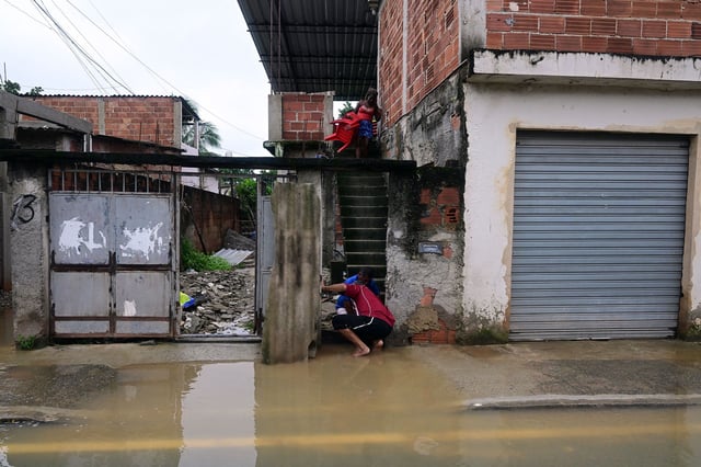 People try to remove water from their flooded house after a rainstorm on the outskirts of Rio de Janeiro on Sunday.