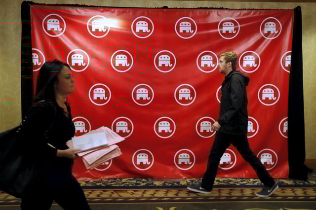 People walk past a banner with the Republican party logo at the Republican National Committee (RNC) summer meetings in Cleveland, Ohio August 5, 2015.  REUTERS/Brian Snyder