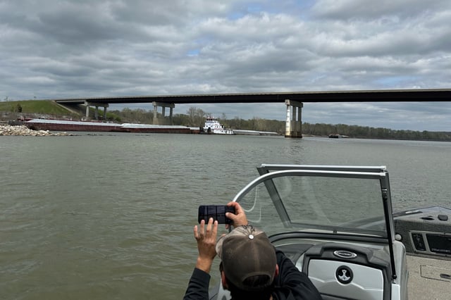 A boater takes a photo of a barge which struck a bridge on the Arkansas River in Sallisaw, Ark., Saturday, March 30, 2024. The Oklahoma State Patrol said Saturday that it closed a highway south of Sallisaw after the collision. (Dayton Holland via AP)