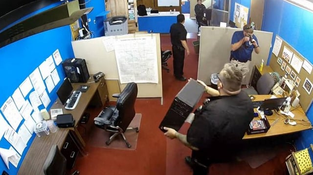 Police officers remove equipment from The Marion County Record’s newsroom in August 2023.