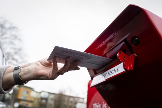 A voter drops off a vote-by-mail ballot on March 12, 2024, during the presidential primary election in Vancouver, Wash.