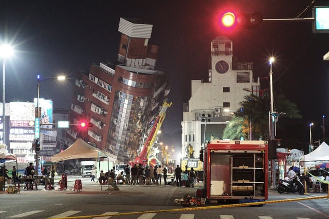 Emergency personnel stand in front of a partially collapsed building leaning over a street in Hualien on April 3, 2024, after a major earthquake hit Taiwan's east.