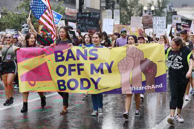 Demonstrators march in the rain during an abortion rights rally in downtown Orlando, Fla., on June 27, 2022.