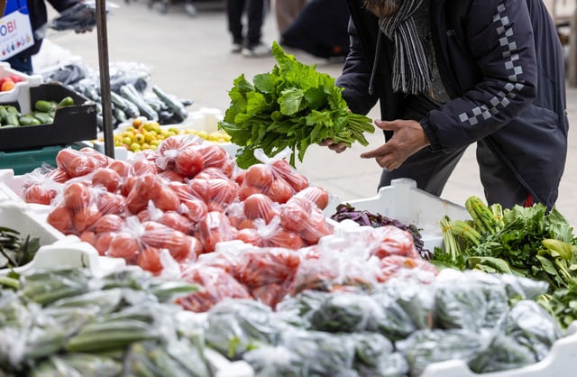 An employee arranges the display on a fresh fruit and vegetable stall in Watney market in London in March 2024.