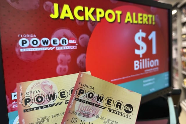 Powerball tickets are shown in front of a screen displaying the estimated jackpot on Wednesday, April 3, 2024, in Surfside, Fla. The Powerball has grown to an estimated $1.3 billion ahead of the drawing on April 6, 2024,