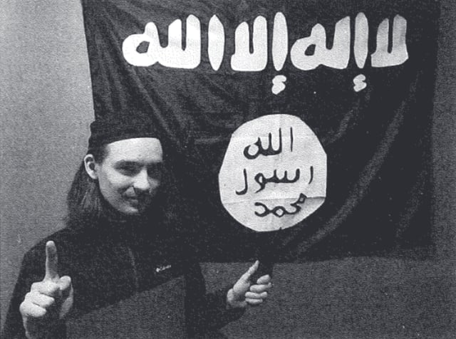 Alexander Scott Mercurio poses with a knife in front of an ISIS flag in a photo included in the Department of Justice's criminal complaint.