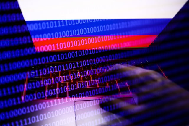 Russian flag displayed on a laptop screen and binary code code displayed on a screen are seen in this multiple exposure illustration photo taken in Krakow, Poland on February 16, 2022. (Photo illustration by Jakub Porzycki/NurPhoto via Getty Images)